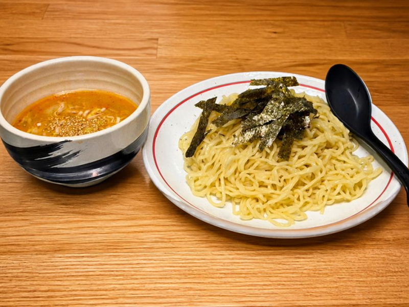 つけ麺処Sin 富士本店のメインメニュー「味噌つけ麺」。木目のテーブルに置かれた、ネギが浮かぶコク深い味噌スープと、海苔がトッピングされた艶やかな麺。