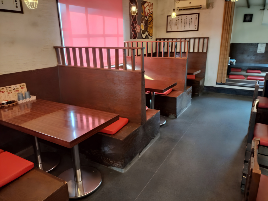富士市のつけ麺店「つけ麺処Sin 富士本店」のテーブル席。木製のパーテーションで仕切られた、赤い座布団のあるボックスタイプのテーブル席です。