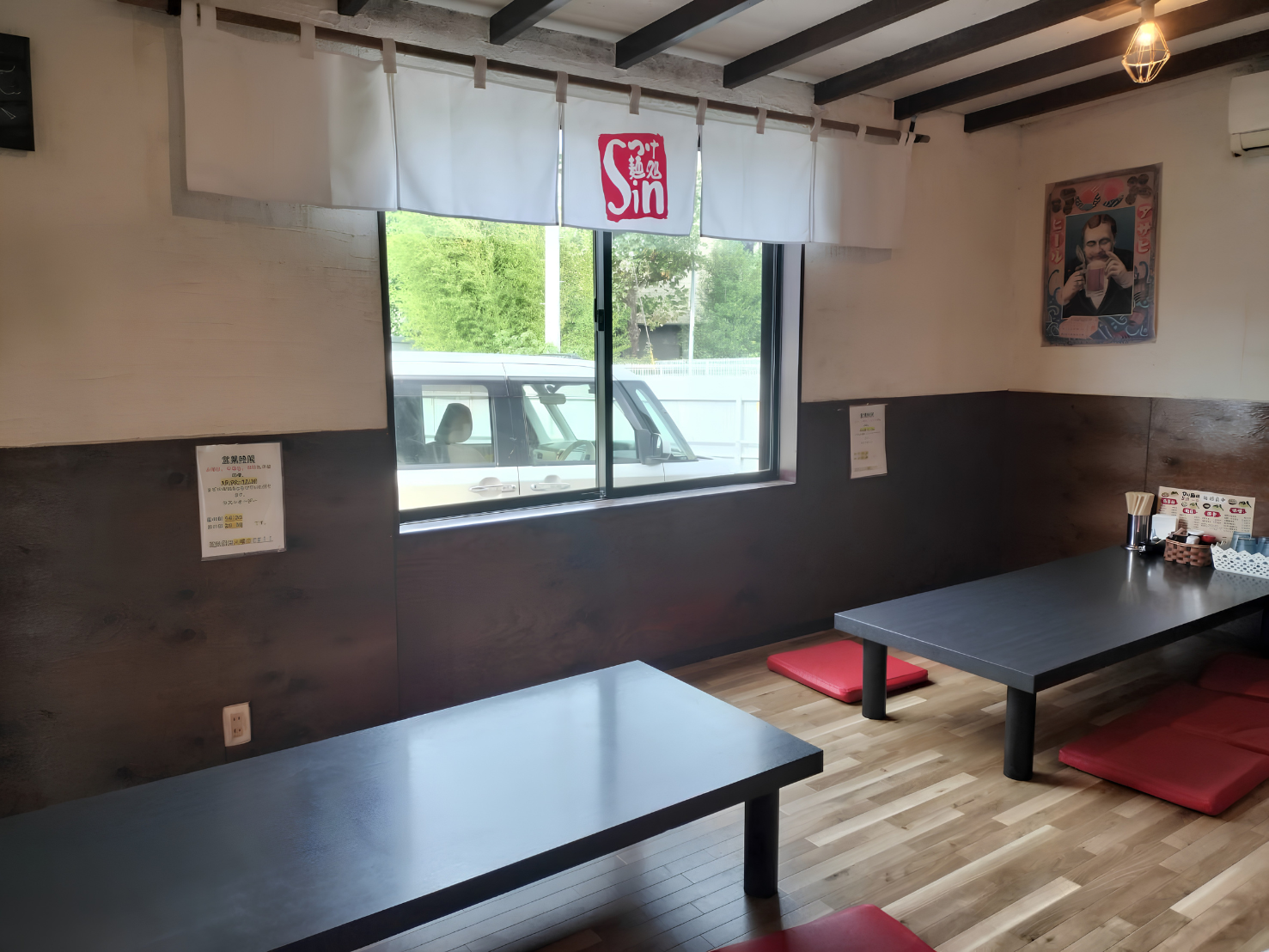 富士市のつけ麺店「つけ麺処Sin 富士本店」のお座敷席。窓から自然光が入る明るい空間に、6名様掛けのローテーブル2卓と赤い座布団が並んでおり、合計12席をご用意しています。